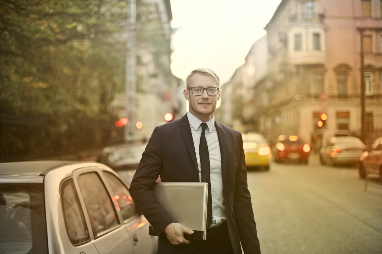 services-05 Businessman in a suit holding a laptop on a busy city street. Urban professional life.