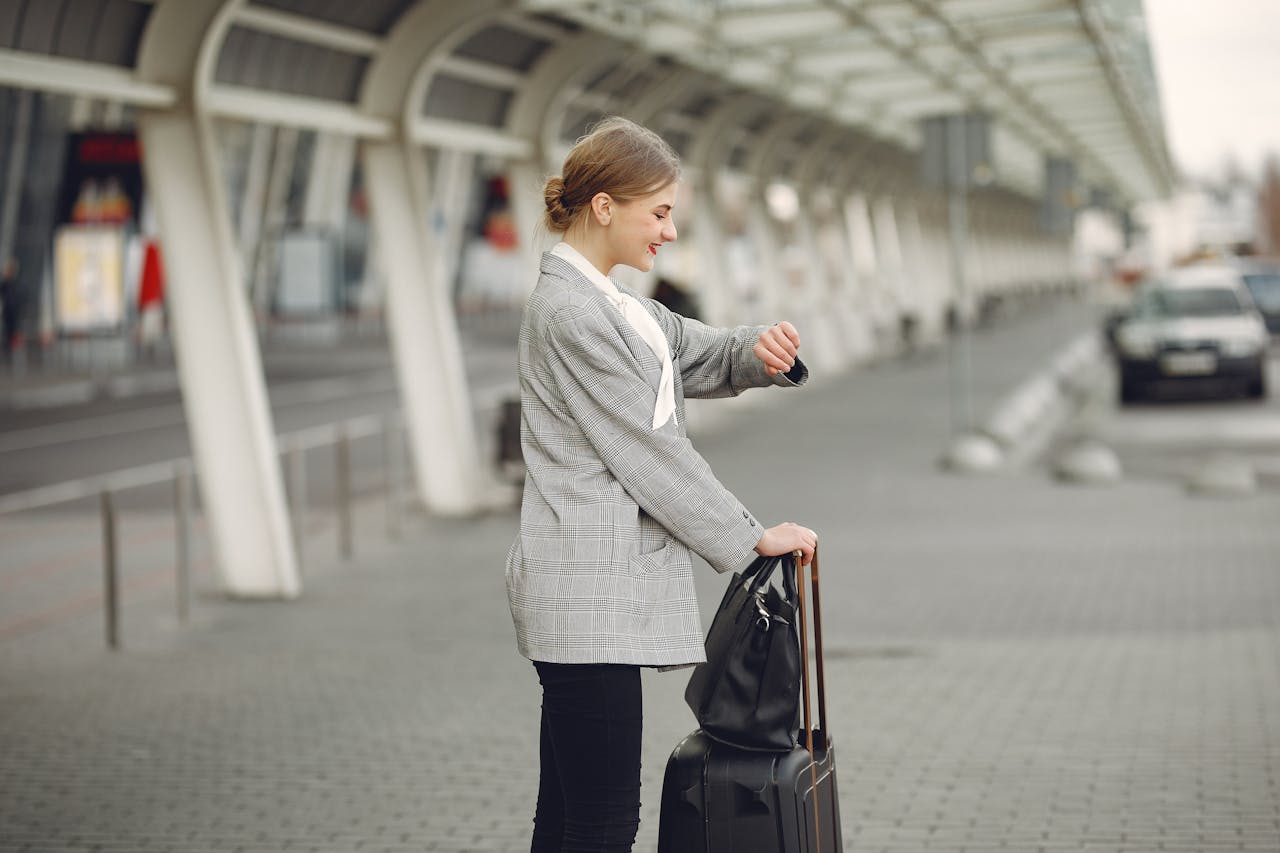 pexels photo 3885597 Woman in gray jacket checking wristwatch at station with luggage, representing punctual travel.